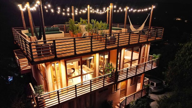 A two-story building with a balcony, string lights, and a hammock. - Ocean Views w/ Rooftop Lounge (Mazunte)