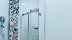 Un baño con lavamanos blanco, un espejo y un secador de pelo en la pared.