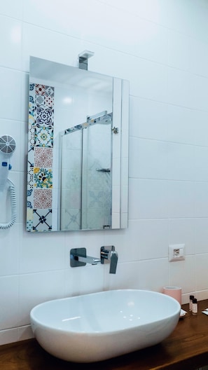 Un baño con lavamanos blanco, un espejo y un secador de pelo en la pared.
