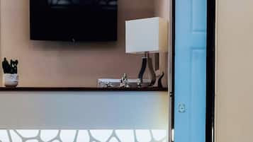 Un'area di accoglienza con una TV a schermo piatto montata a parete, un lampadario decorativo e un elemento decorativo a parete con motivo.
