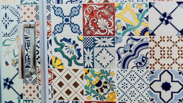 Una pared con diversos diseños de azulejos coloridos, incluyendo motivos florales y geométricos.