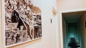 Un pasillo con una fotografía en blanco y negro de un pueblo montañoso y una escalera que conduce a otra habitación.