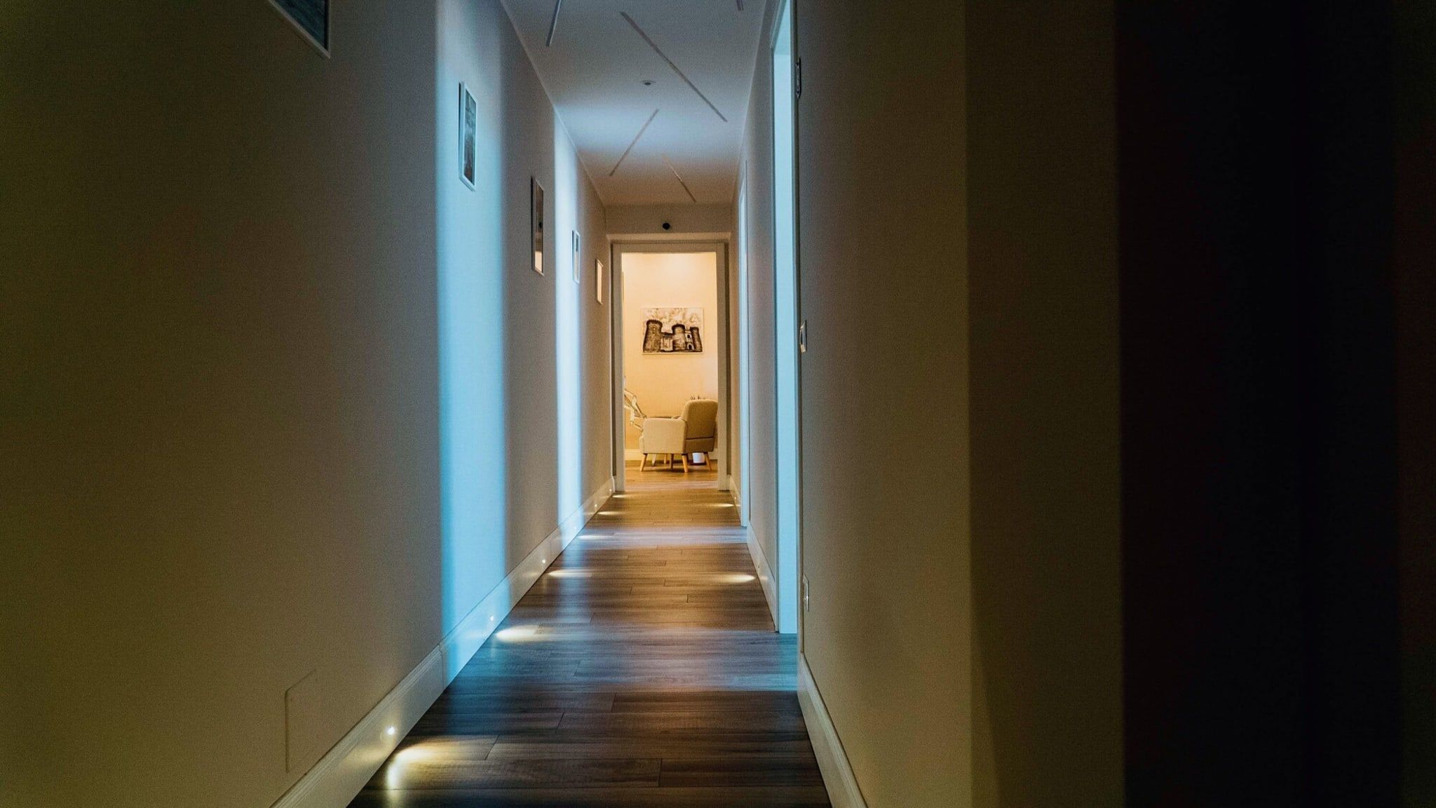 A narrow hallway with wooden flooring and light-colored walls.