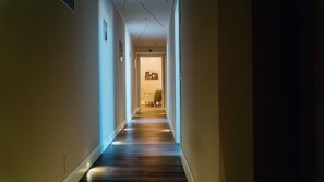 Corredor estreito com soalho de madeira e paredes claras.