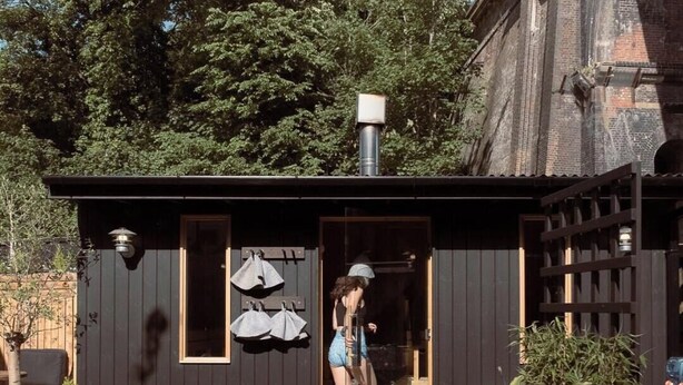 A small wooden structure with a door, a bench, and a table outside.