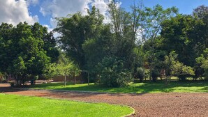 A park with a grassy area, trees, and a gravel path. - El manantial de Iguazu (Puerto Iguazú)