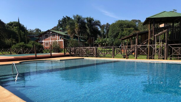 A clear blue pool with a wooden deck and a gazebo in the background. - El manantial de Iguazu (Puerto Iguazú)