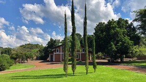 A house with a brick exterior, surrounded by a well-maintained lawn and tall trees. - El manantial de Iguazu (Puerto Iguazú)