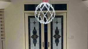 Une pièce avec une porte blanche ornée de panneaux de verre décoratifs et un lustre au plafond.