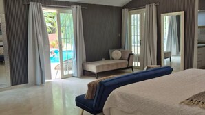 Une chambre moderne dotée d’un grand lit, d’un coin salon et offrant une vue sur une piscine.