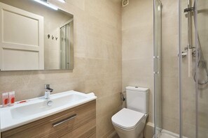 A modern bathroom with a sink, mirror, toilet, and glass shower enclosure. - BBarcelona Calabria Flat (Barcelona)
