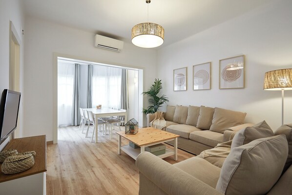A modern living room with a sofa, a coffee table, and a dining area with chairs and a table. - BBarcelona Calabria Flat (Barcelona)