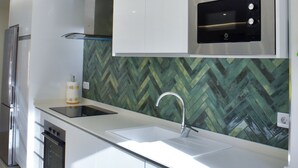 Een moderne keuken met witte kasten, een roestvrijstalen oven en een backsplash met een visgraatmotief.