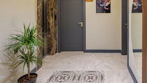 A hallway with a marble floor, a potted plant, a door labeled '201', and two wall-mounted paintings. - Yeşilton Otel (Arhavi)