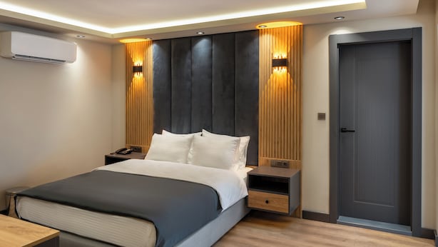 A modern bedroom with a large bed, bedside tables, an air conditioning unit, and a door. - Yeşilton Otel (Arhavi)
