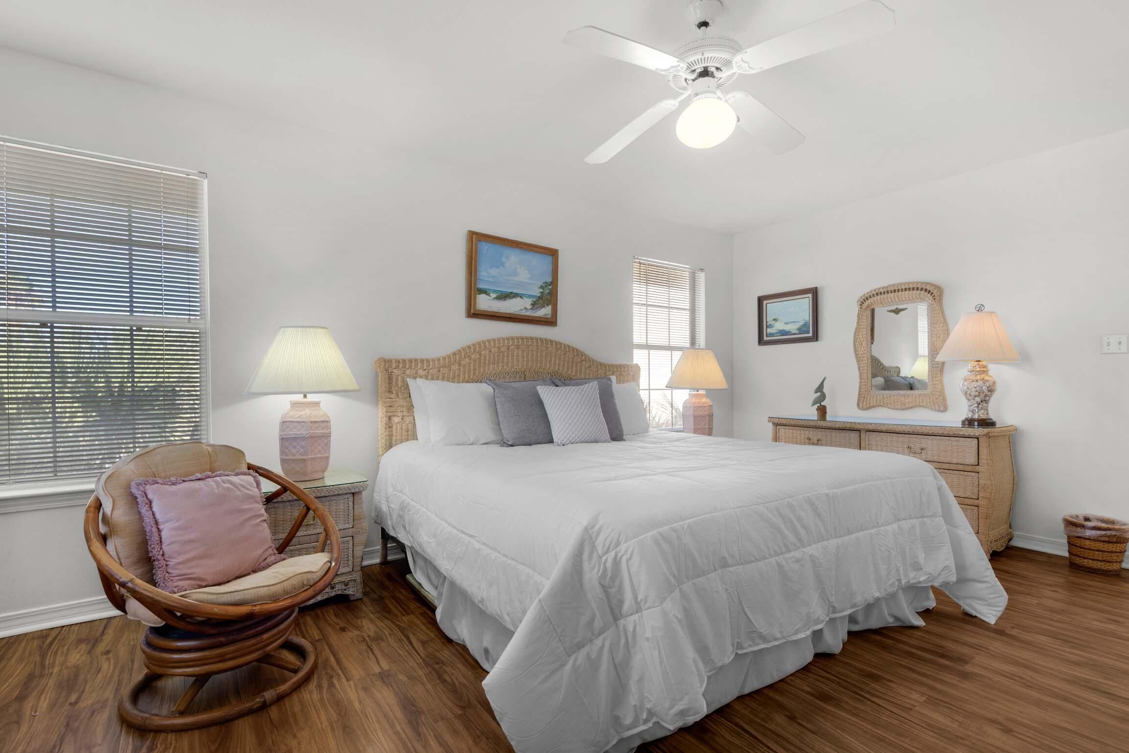 A bedroom with a large bed, a rocking chair, a dresser, and a ceiling fan.