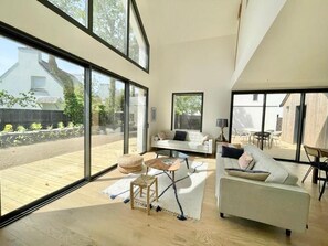 Amplia sala de estar con ventanas grandes, un sofá, una mesa de centro y una alfombra.