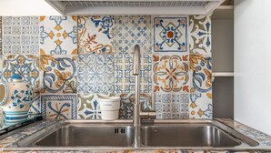 A kitchen with a double sink and colorful tile backsplash.