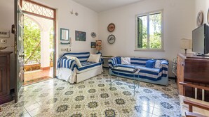 A living room with two striped sofas, a coffee table, and a television.