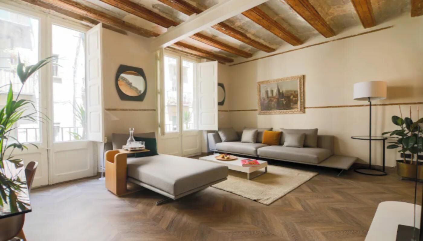 Una sala de estar con sofá, reposapiés, mesa de centro y lámpara.