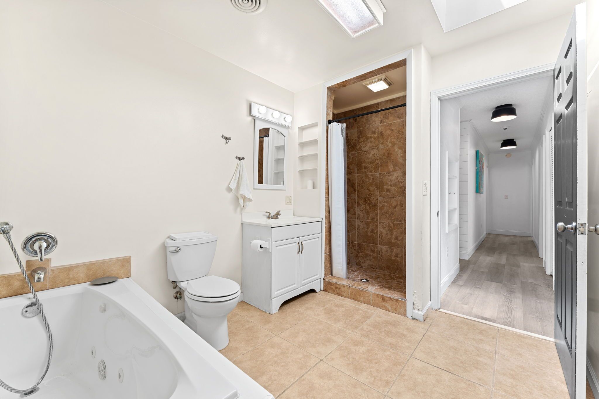 Un baño moderno con bañera, inodoro, tocador y zona de ducha.
