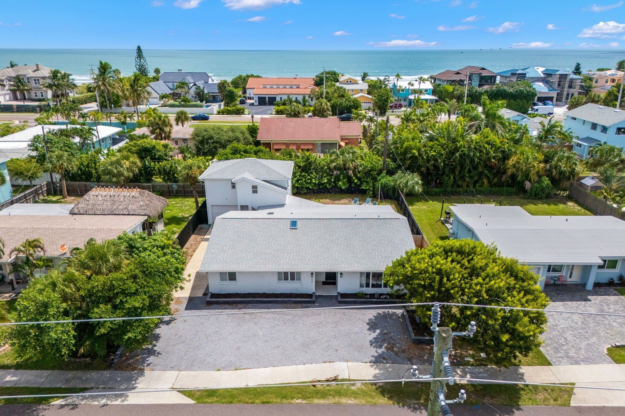 A residential area with houses, a clear view of the ocean, and a well-maintained lawn.