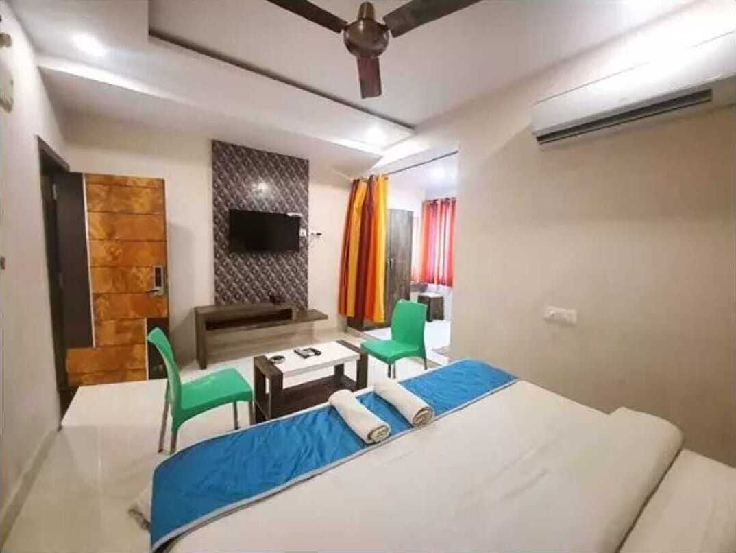 A hotel room with a bed, a desk, a chair, a television, and a ceiling fan.
