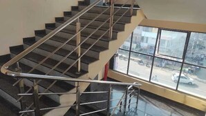 Eine Treppe mit Metallgeländern und Blick auf die Straße durch große Fenster.