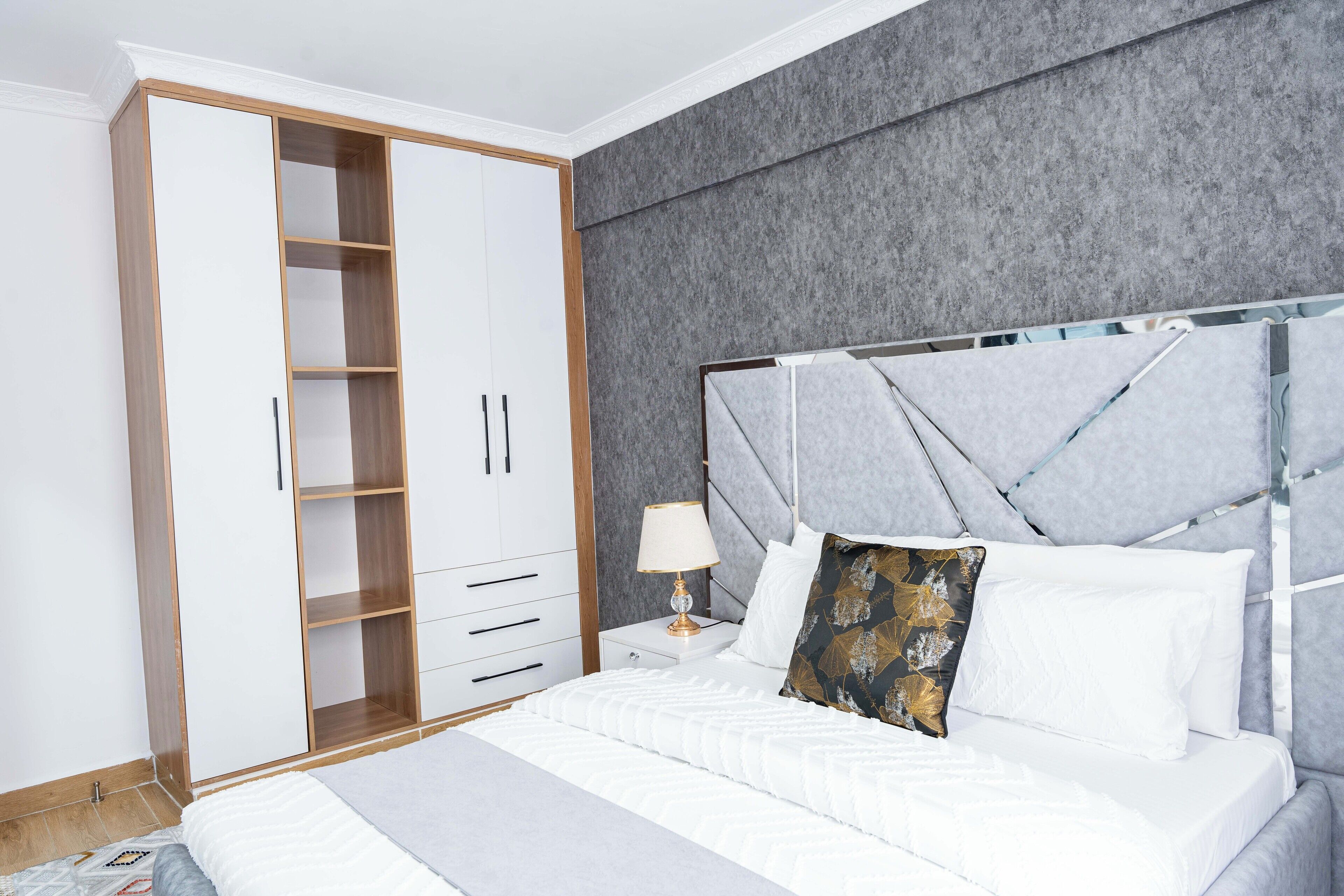 A bedroom with a bed, a wardrobe, and a nightstand.
