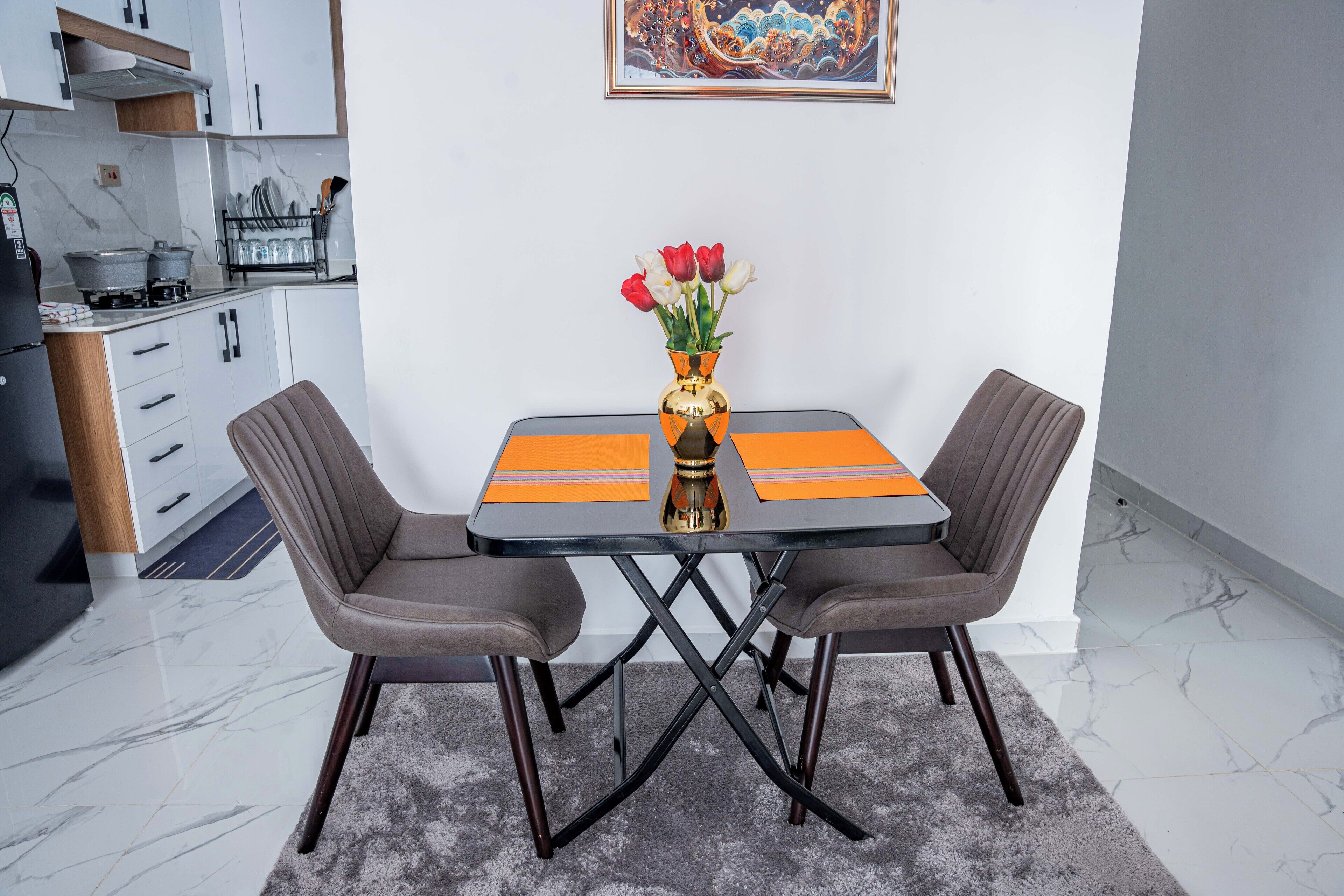 A modern kitchen with white cabinets, a black countertop, and a dining area with a table and two chairs.