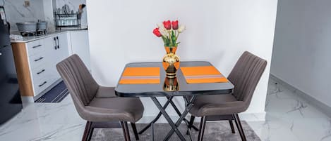 A modern kitchen with white cabinets, a black countertop, and a dining area with a table and two chairs.