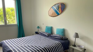 A bedroom with a striped bedspread, teal pillows, a wall-mounted decorative item, a bedside table with a lamp, and a bowl. - 4-bedroom villa, private heated pool, enclosed garden8 minutes from the beach (Linxe)