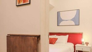 Une chambre d’hôtel avec un lit, une table de chevet, une armoire en bois et des œuvres d’art abstrait accrochées aux murs.