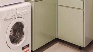 Une petite cuisine équipée d’un lave-linge, d’un évier et d’un placard.