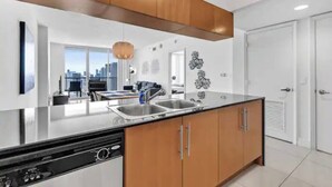 A modern kitchen with a central island, stainless steel appliances, and wooden cabinetry. - Edgewater High-Rise | Stunning Bay Views + Gym (Miami)