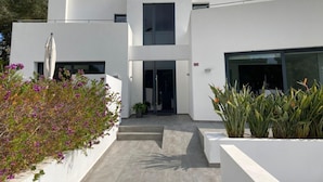 A modern two-story building with a flat roof, large windows, and a central entrance.