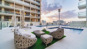 A rooftop pool area with outdoor seating and a city view. - Quiet Top-Floor Studio Near Metro + Baby Gear (Dubai)