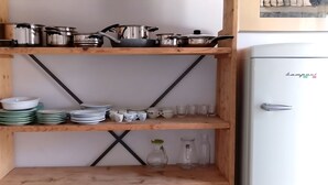 A kitchen with wooden shelves holding pots, pans, plates, and cups. - APARTMENT CORRIDORS 60 (Firenze)