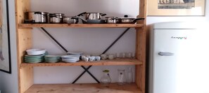 A kitchen with wooden shelves holding pots, pans, plates, and cups. - APARTMENT CORRIDORS 60 (Firenze)