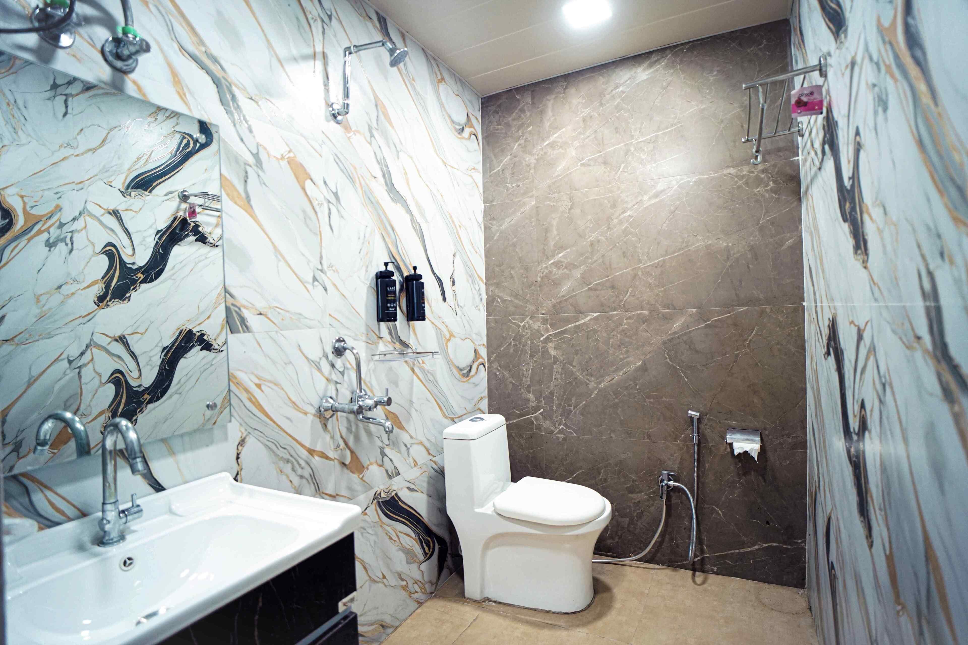 A bathroom with a marble sink, a toilet, and a shower area.