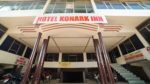La entrada principal del Hotel Konark Inn con un letrero sobre la puerta, una escalera que conduce al piso superior y un cartel de Asian College of Nursing al fondo.