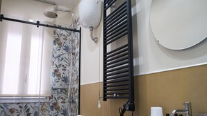 Een badkamer met toilet, bidet, douche en wastafel met toiletartikelen.