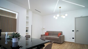 Een moderne woonkamer met een glazen eettafel, een bank en een minimalistisch design.