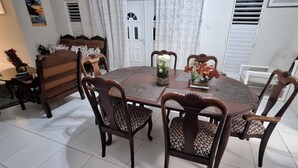 A dining area with a round table, six chairs, and a vase with flowers. - Cottage at Coverley (Christ Church)