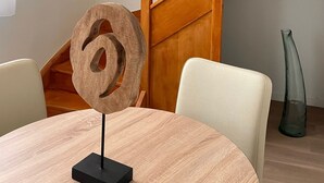 A modern interior with a round wooden table, a unique sculpture, and a wooden staircase. - Zenao Appart'hôtels Cognac (Cognac)