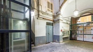 A narrow stone-paved courtyard with a metal gate, a blue door, and a window with a metal frame. - Modern Spacious Apartment in the Heart of Naples (Naples)
