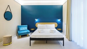 A modern hotel room with a large bed, a blue armchair, and a round wall decoration. - Modern Spacious Apartment in the Heart of Naples (Naples)
