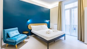 A modern bedroom with a bed, a blue sofa, and a large window. - Modern Spacious Apartment in the Heart of Naples (Naples)