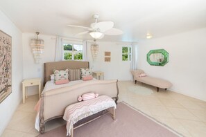 Un dormitorio con cama, banca, ventilador de techo y espejo verde.