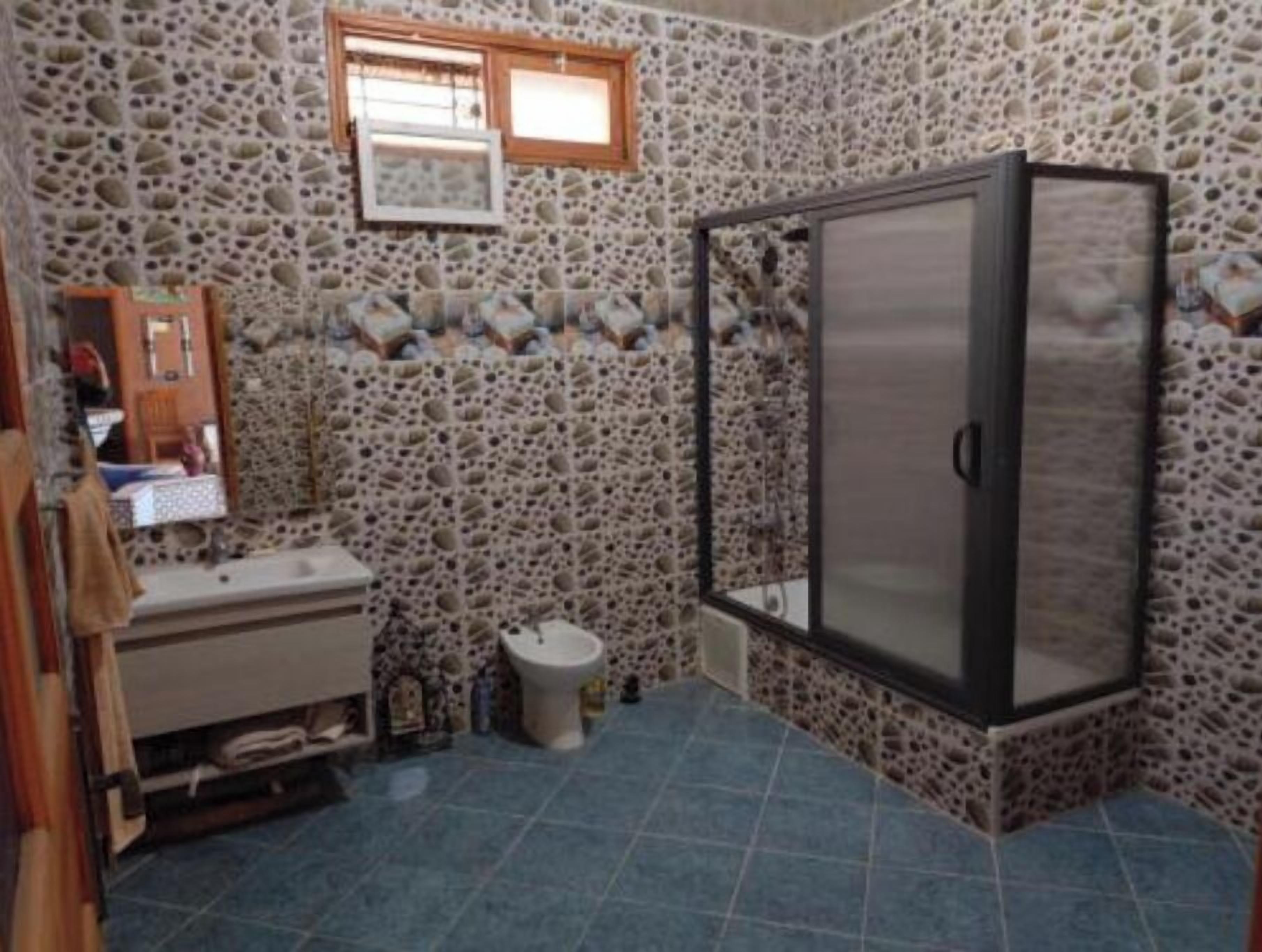 Une salle de bain avec des murs en pierre, un lavabo, des toilettes et un espace douche.
